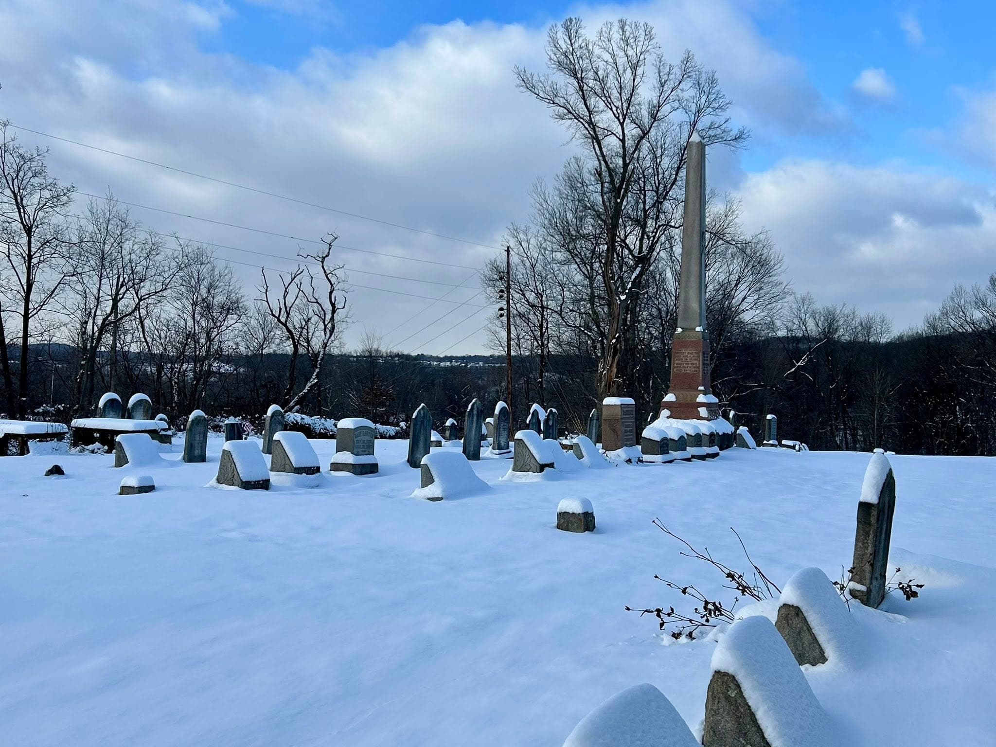 Cemetery monuments and headstones in winter snow.